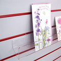 Side profile of standard greeting card rack installed on white slatwall.